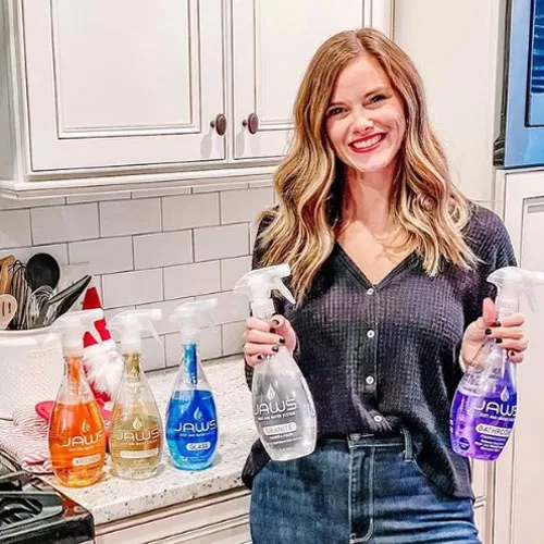 Woman holding JAWS cleaning products in a kitchen