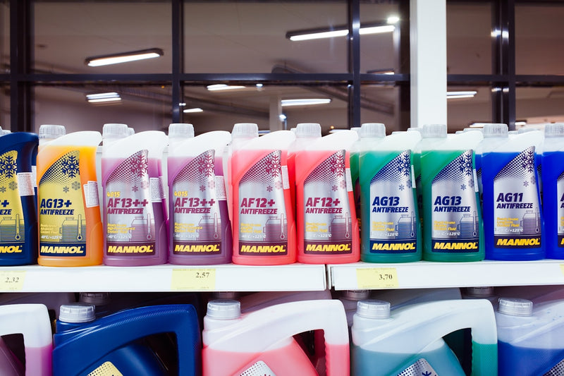 Shelf with various bottles of Mannol antifreeze and coolant on a store shelf.
