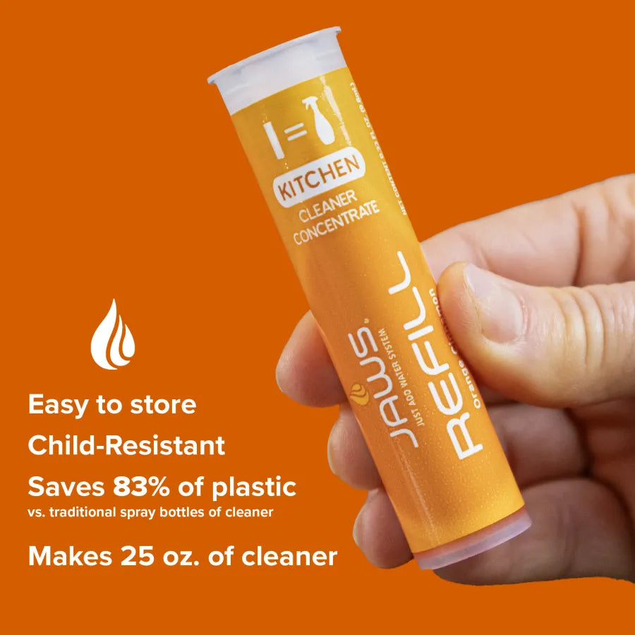 Hand holding a JAWS kitchen cleaner refill pod against an orange background.