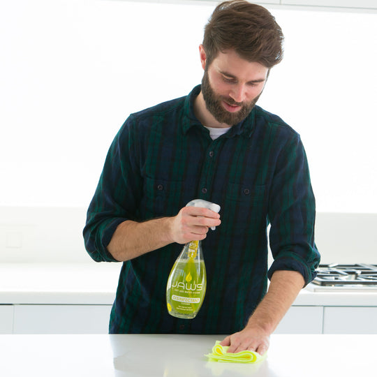 Man cleaning a white kitchen surface with JAWS Disinfectant Cleaner and yellow microfiber cloth.