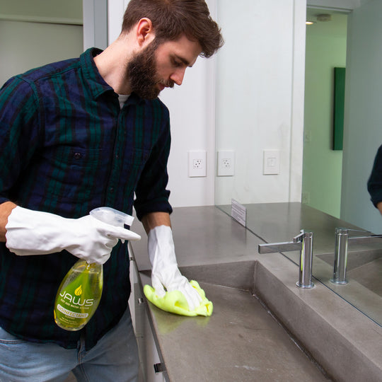 Man cleaning a sink with JAWS Disinfectant Cleaner in a bathroom setting.