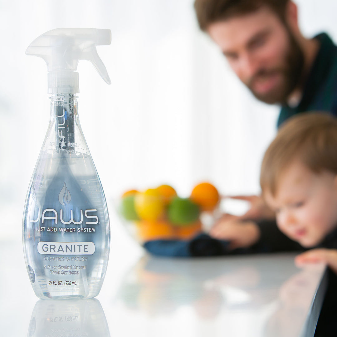 Bottle of JAWS Granite Cleaner with a blurred background of a man and child looking at reflection.
