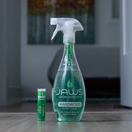 JAWS hardwood floor cleaner bottle with refill pod on a wooden floor.