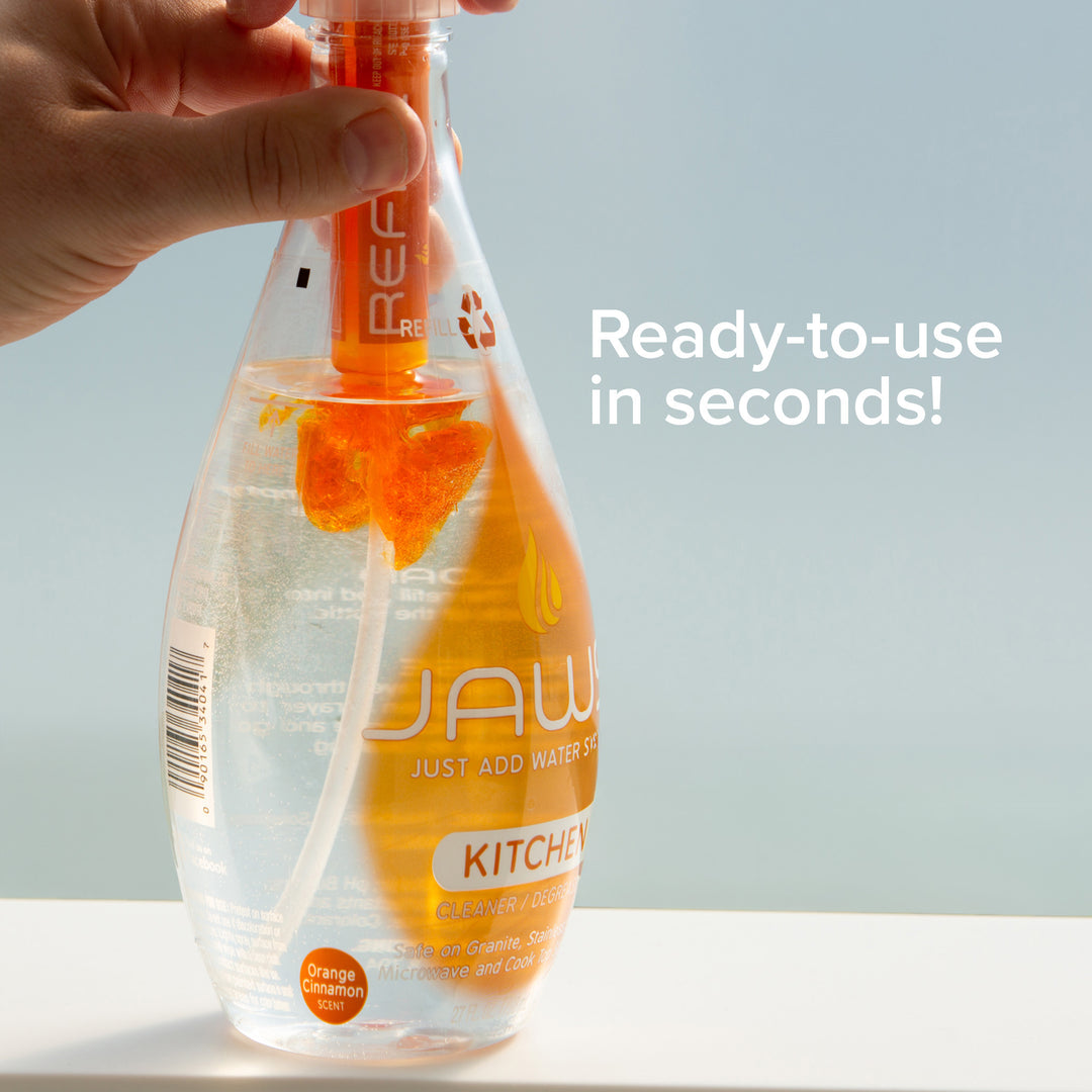 JAWS Kitchen spray bottle with orange refill pod releasing orange cleaner into the bottle with text "Ready-to-use in seconds: on a light background.