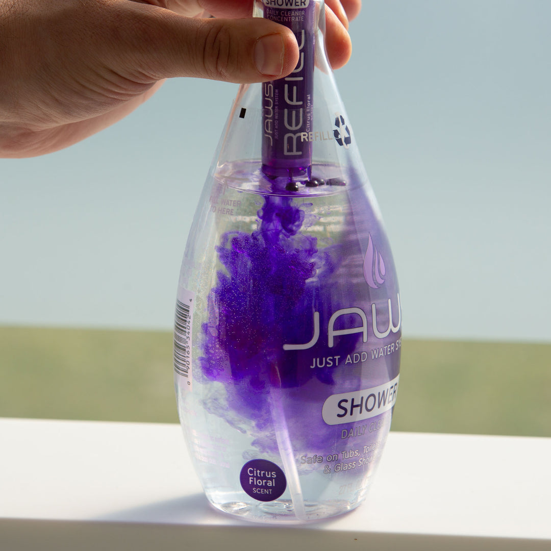 JAWS Shower Cleaner Bottle with refill pod releasing purple concentrate into bottle.