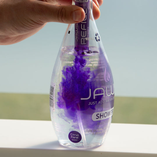 JAWS Shower Cleaner Bottle with refill pod releasing purple concentrate into bottle.