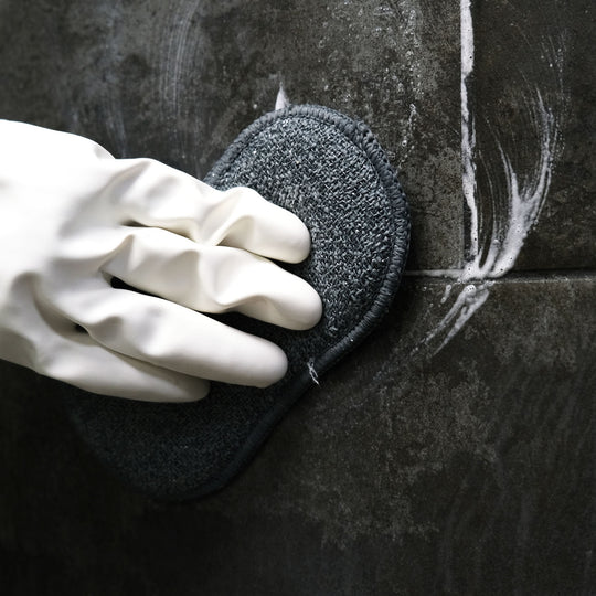 Hand wearing a white glove wiping cream cleanser off surface.