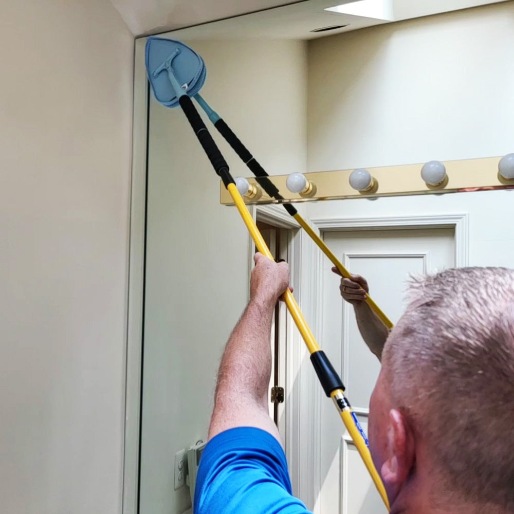 Man cleaning bathroom mirror with extension added to JAWS cleaning wand