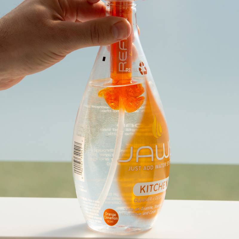 JAWS Kitchen Cleaner bottle with refill in neck releasing orange concentrate into bottle. 