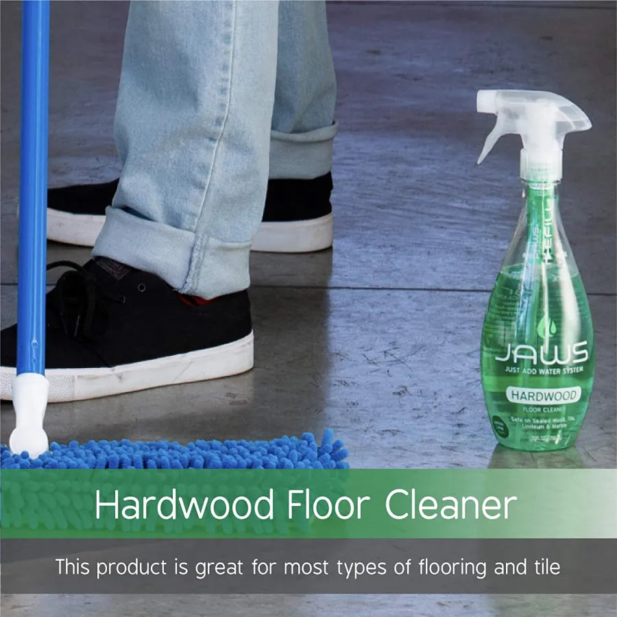 Hardwood floor cleaner spray bottle on concrete floor next to feet of person mopping.  