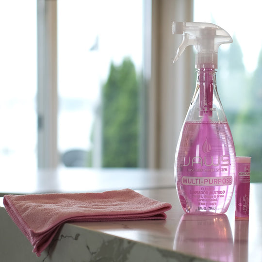 JAWS Pink multi-purpose cleaner with a pink microfiber cloth on a reflective surface.